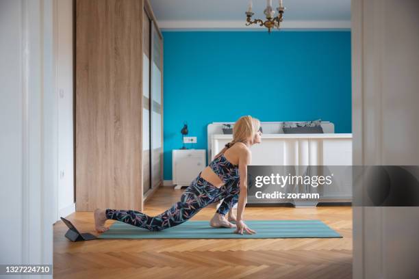 woman practicing yoga in equestrian riding horse lunge pose on exercise mat in bedroom - lunge imagens e fotografias de stock