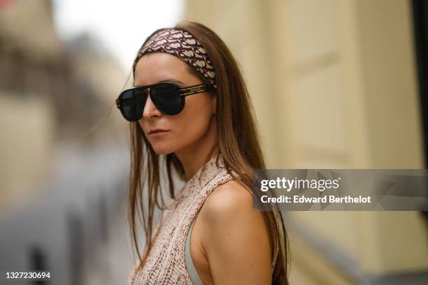 Julia Comil wears sunglasses, a brown and beige Dior Oblique Jacquard headband from Dior, a brown and beige braided wool asymmetric pullover, outside...