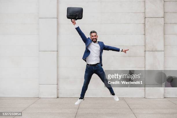 happy businessman with briefcase jumping on footpath - jumping imagens e fotografias de stock