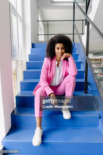 female entrepreneur with hand on chin sitting on steps at office - black trouser suit stock pictures, royalty-free photos & images