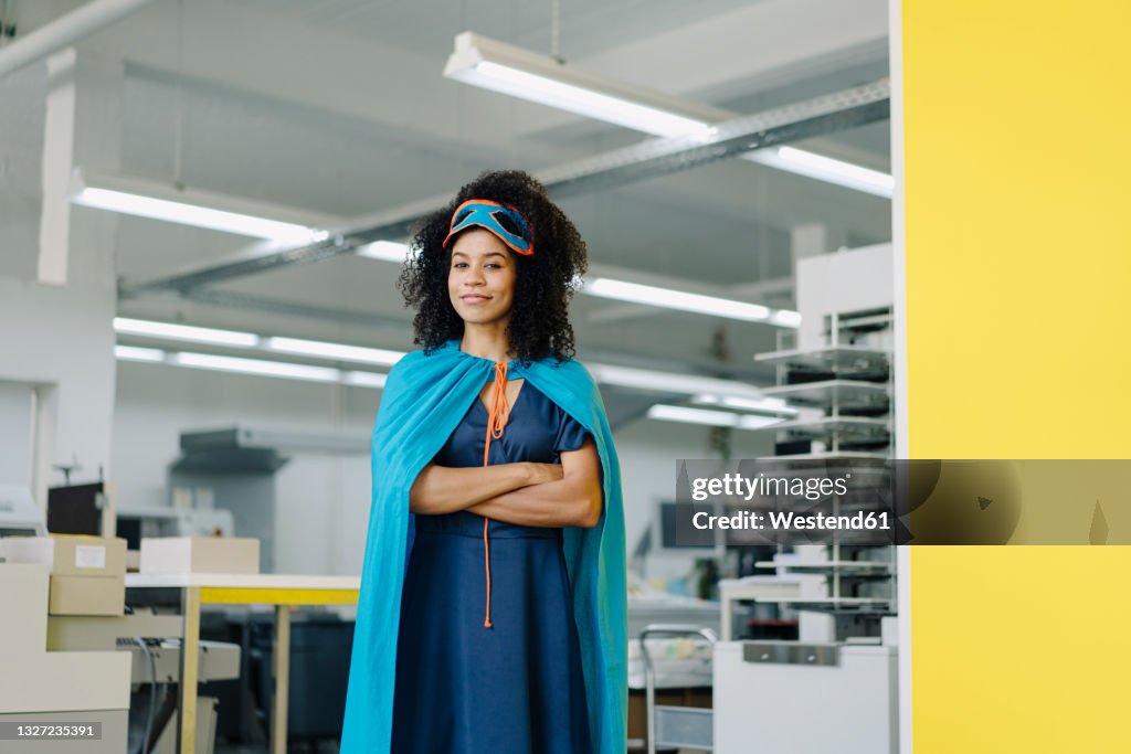 Businesswoman in superhero costume standing in industry