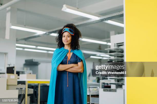 businesswoman in superhero costume standing in industry - role play stockfoto's en -beelden