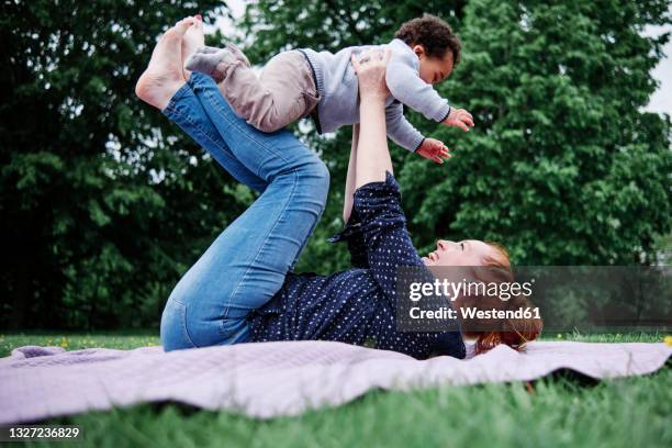 mother picking son on leg while playing at park - 飛行機のまね ストックフォトと画像