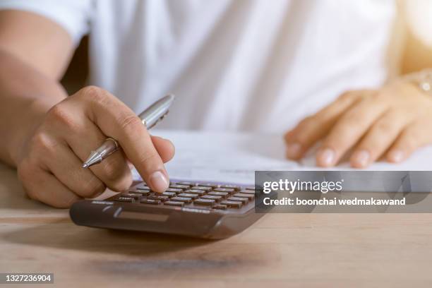 young woman writing make note and doing calculate finance at home office. - price calculator stockfoto's en -beelden