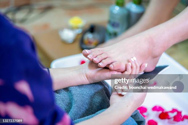 woman enjoying a feet massage in a spa setting (close up on feet) - fußpflege stock-fotos und bilder