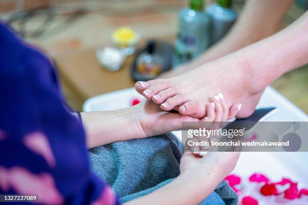 woman enjoying a feet massage in a spa setting (close up on feet) - pedicure stockfoto's en -beelden