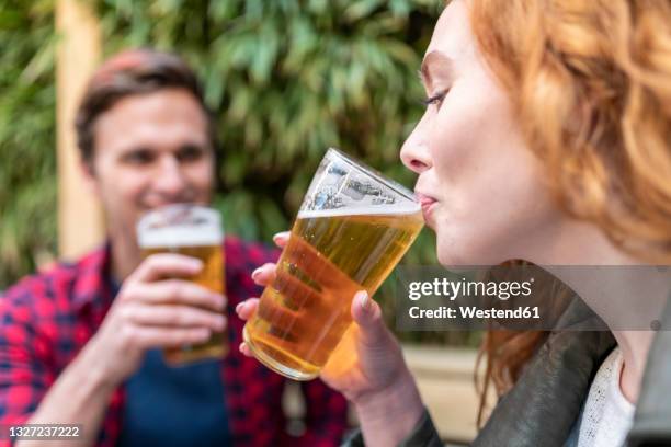 woman drinking beer in glass at pub - beer close up foto e immagini stock