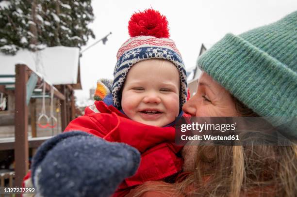 smiling woman looking at cheerful son while standing at backyard during winter - holland achtertuin stockfoto's en -beelden