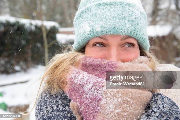 mature woman covering face with scarf during winter looking away - woman face hat foto e immagini stock