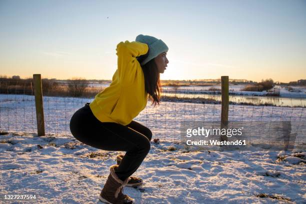 mature woman wearing knit hat practicing squats during winter - hands behind head stock pictures, royalty-free photos & images