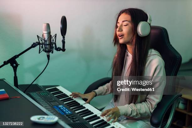 young female singer singing while playing piano in studio - pianist front stock pictures, royalty-free photos & images