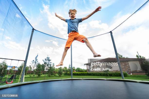 kleiner junge springt auf dem trampolin - trampoline stock-fotos und bilder