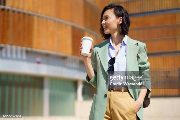 beautiful businesswoman with hand in pocket holding reusable coffee cup - coffe to go stock pictures, royalty-free photos & images