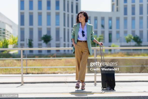 businesswoman with wheeled luggage waiting for train at railroad station - young woman trolley stock-fotos und bilder