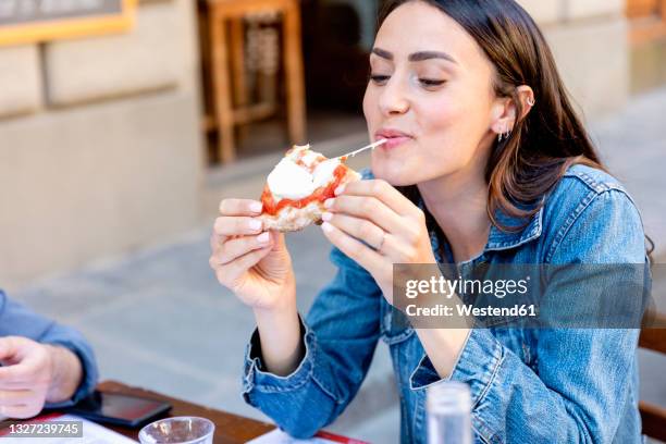 smiling woman eating pizza at sidewalk cafe - italian cafe culture stock pictures, royalty-free photos & images