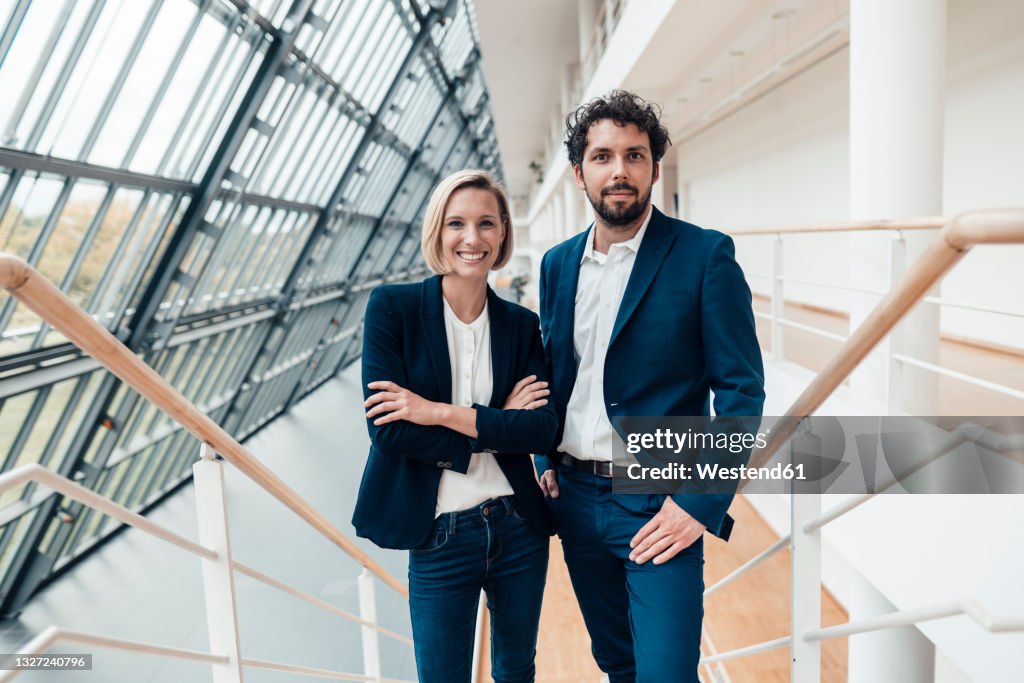 Businesswoman with arms crossed standing by colleague at office
