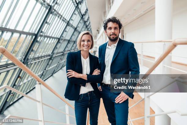 businesswoman with arms crossed standing by colleague at office - two males stock pictures, royalty-free photos & images