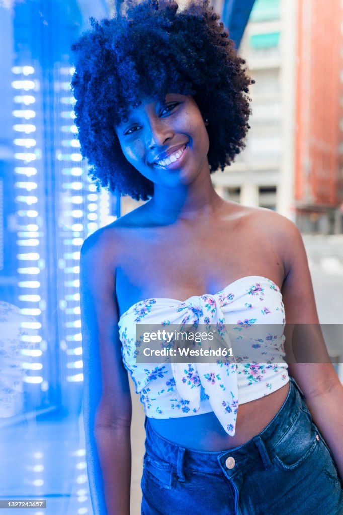 Smiling woman standing at neon lighting