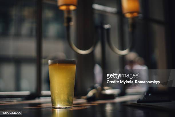 glass of the foaming cold beer on the table - pilsner - fotografias e filmes do acervo