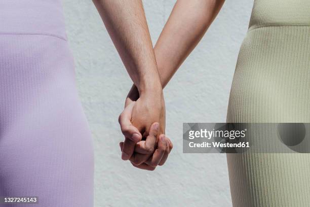 sportswomen holding hands while standing in front of wall - twisted together stock pictures, royalty-free photos & images