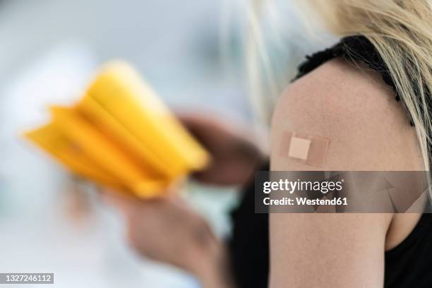 woman with bandage on arm at vaccination center - vaccination center stock-fotos und bilder