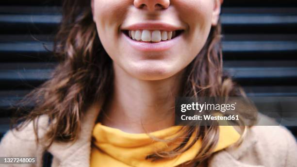 young woman smiling near shutter - dientes humanos fotografías e imágenes de stock