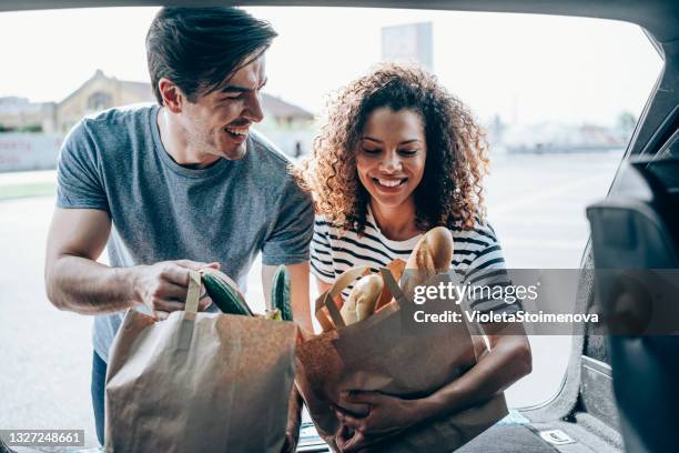 車のトランクに食料品を梱包する若い家族。 - couple in car ストックフォトと画像