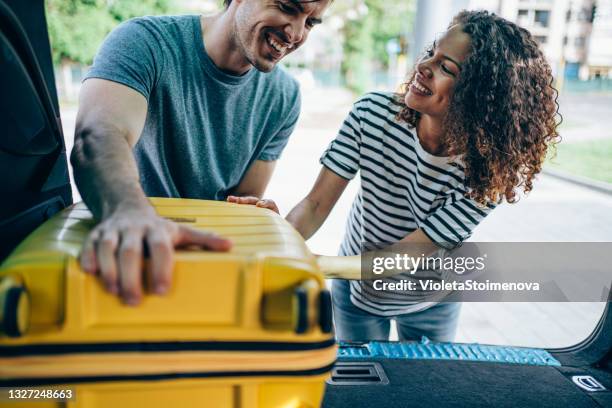 pareja joven empacando y cargando equipaje en el maletero del coche para sus vacaciones. - bagage fotografías e imágenes de stock