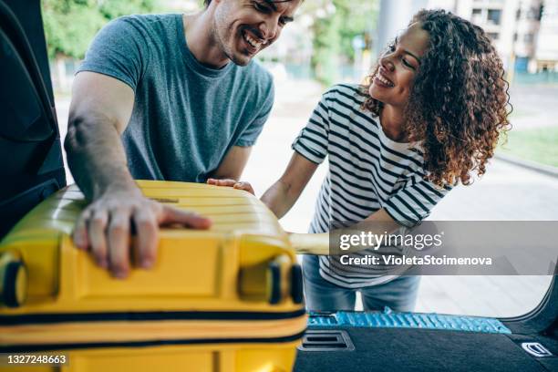 young couple packing and loading luggage into car trunk for their vacation. - husband stock pictures, royalty-free photos & images