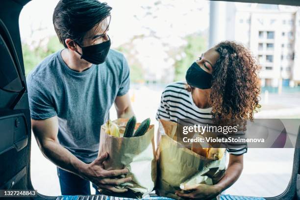 couple putting groceries in a car trunk. - supermarket mask stock pictures, royalty-free photos & images