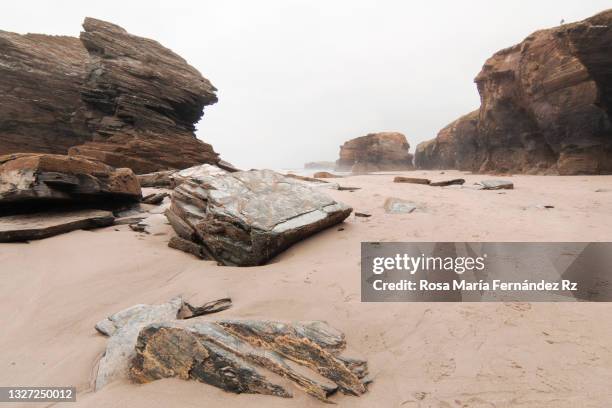 rocky shore on cathedrals beach in low tide at a foggy and overcast day, spain - rosa rock stock pictures, royalty-free photos & images