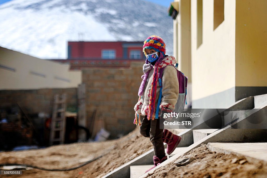 A Tibetan girl walks outside her new hou