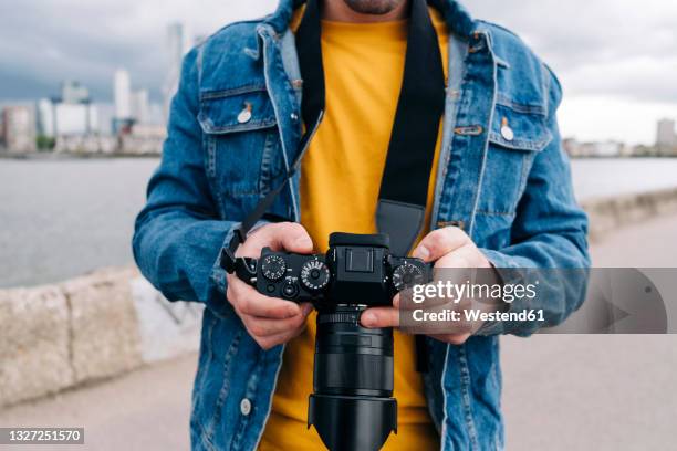 young man operating camera on promenade - camera operator stock pictures, royalty-free photos & images