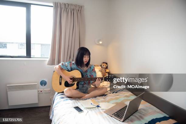 a young asian female musician is composing music with her computer and guitar - woman in guitar making studio stock pictures, royalty-free photos & images