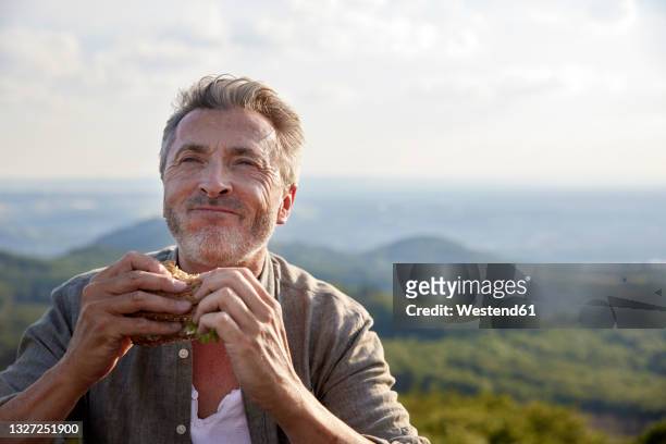 man smiling while holding sandwich - beißen stock-fotos und bilder