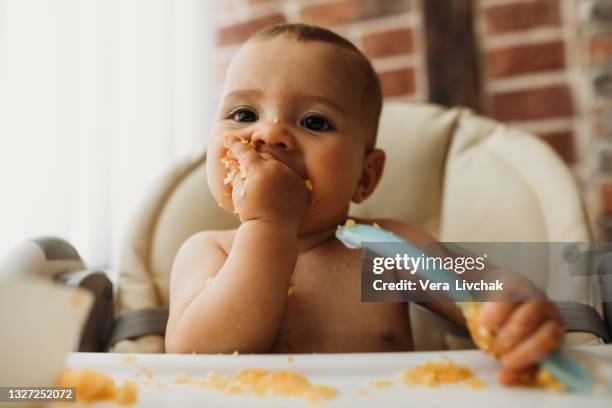 funny baby eating healthy food on kitchen - baby eating food stock pictures, royalty-free photos & images