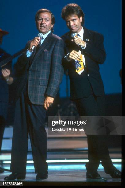 Singer Cliff Richard duetting with Des O'Connor on the set of variety chat show Des O'Connor Tonight, circa October 1989.
