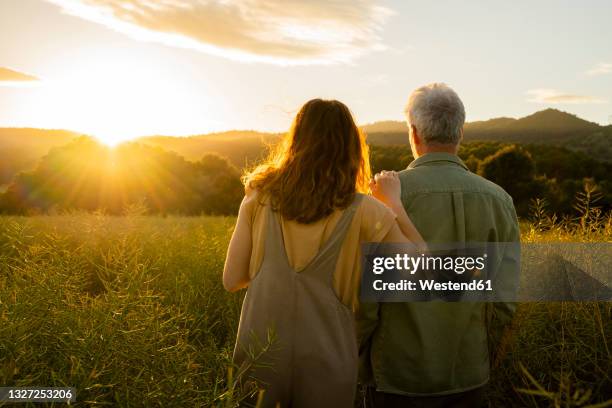 daughter and father looking at sunset view while standing at in field - father and grown up daughter stock-fotos und bilder