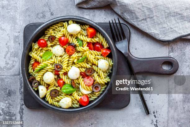 bowl ofready-to-eatpasta salad with cherry tomatoes, olives, mozzarella cheese and basil - pasta salad stock pictures, royalty-free photos & images