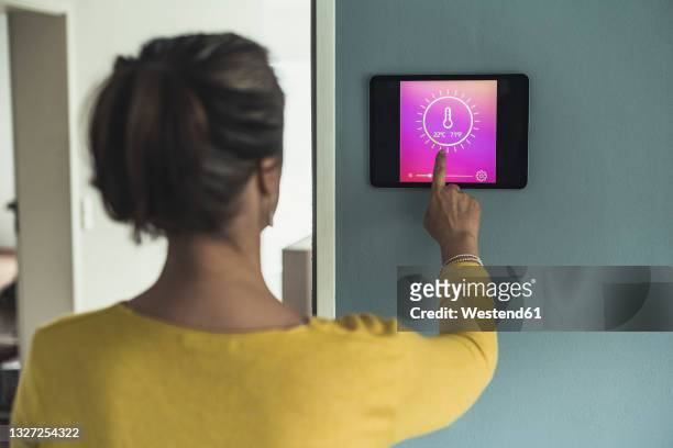 woman using home automation device on wall - termostato - fotografias e filmes do acervo