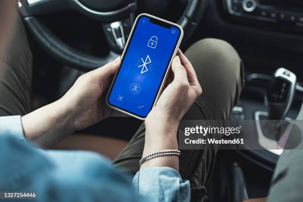 woman accessing bluetooth on mobile phone in car - bluetooth stock-fotos und bilder