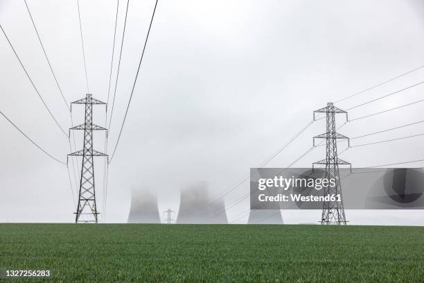 uk, england, rugeley, electricity pylons standing in field during foggy weather with cooling towers in background - electricity pylon bildbanksfoton och bilder