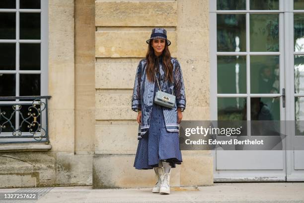 Tamara Kalinic wears a transparent and blue Dior Oblique Jacquard bob / hat, a matching transparent and blue Dior Oblique Jacquard long rain coat, a...