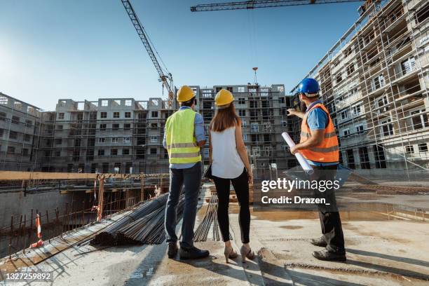 unrecognizable employees on construction site, showing the building and cranes - real estate developer stock pictures, royalty-free photos & images