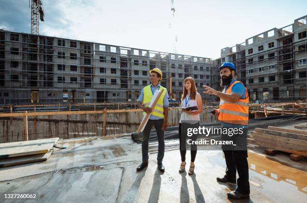 blue collar workers and engineers on construction site with crane - property developer stock pictures, royalty-free photos & images