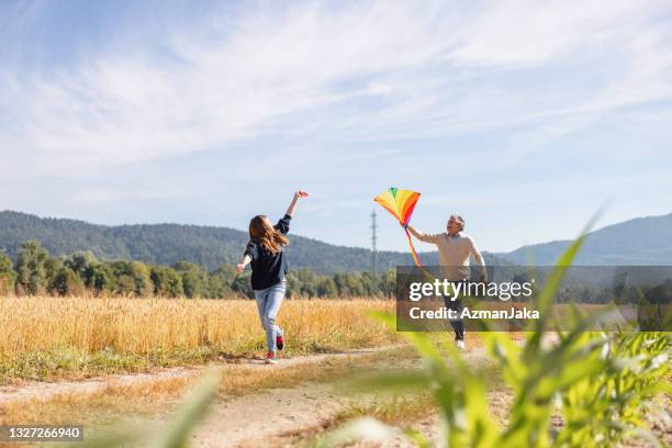nonno e sua nipote che volano un aquilone all'aperto e si divertono - kite toy foto e immagini stock