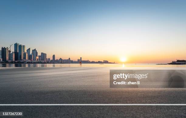 asphalt road by the sea at sunrise - city sky fotografías e imágenes de stock