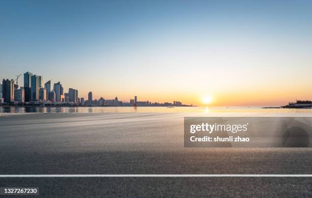 asphalt road by the sea at sunrise - aurora foto e immagini stock