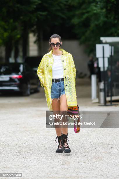 Guest wears sunglasses, a white t-shirt, a black shiny grained leather belt, blue ripped denim jeans shorts, black shiny leather cut-out laces ankle...