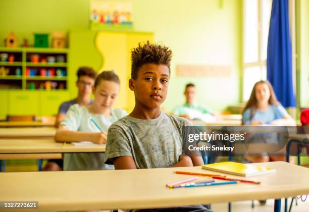 young african american boy sitting in classroom. - 13 pencils stockfoto's en -beelden